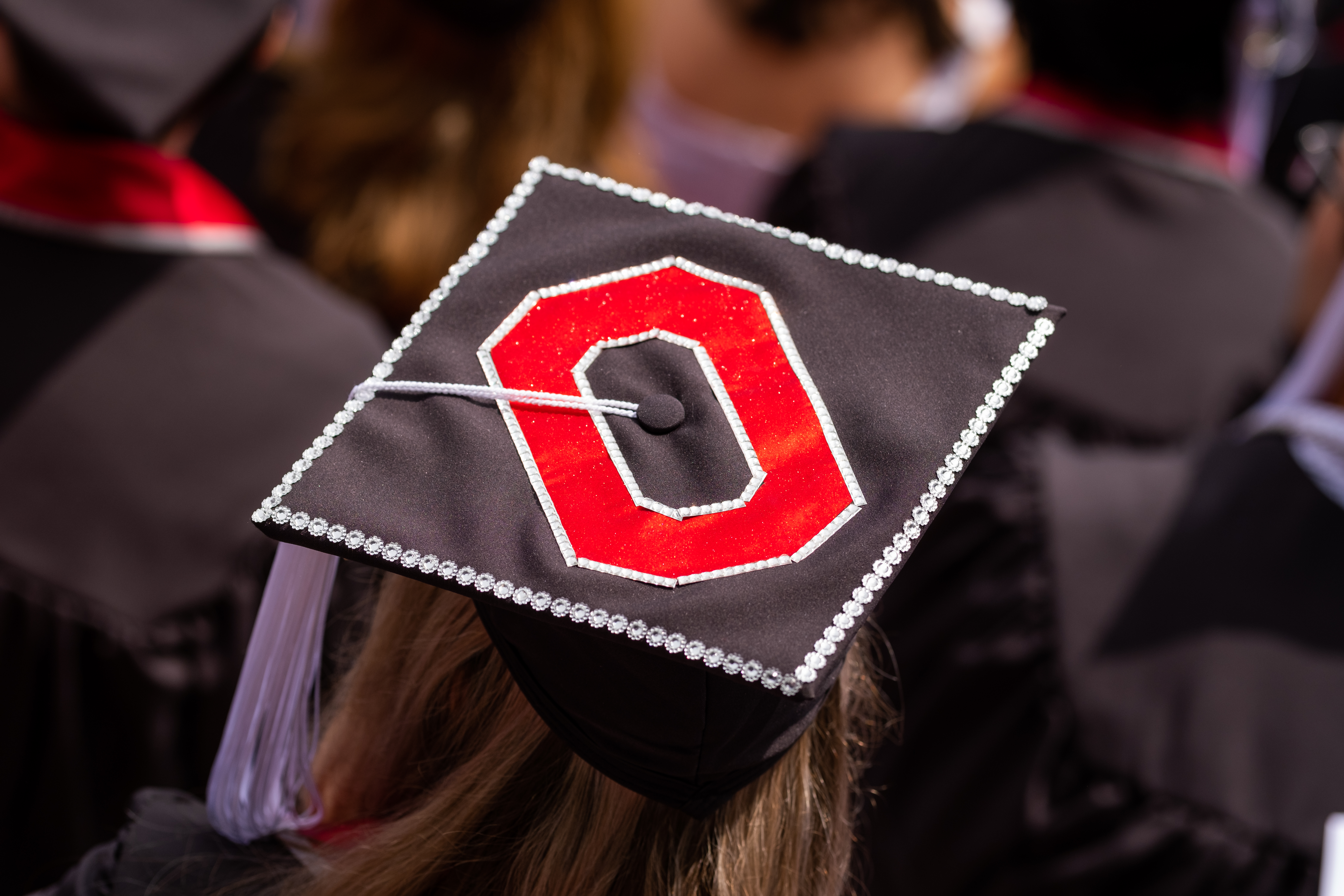 Student wearing graduation cap with Block O logo